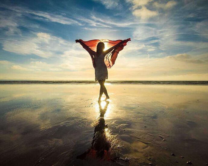 Frau steht im Wasser am Strand und Freud sich