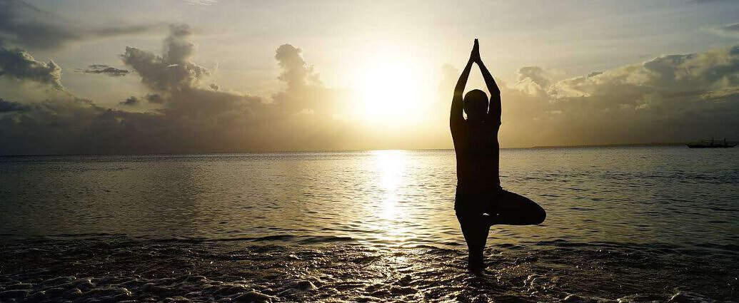 Zu sehen ist eine junge Frau, die im Wasser steht und meditiert.