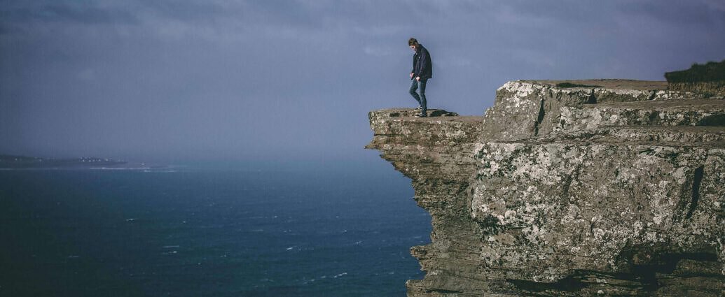 Ein Mann steht auf einer Klippe und blickt in die Ferne.