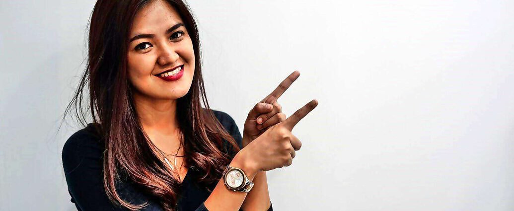 Eine junge Frau, die lacht und eine Geste mit den Fingern macht.