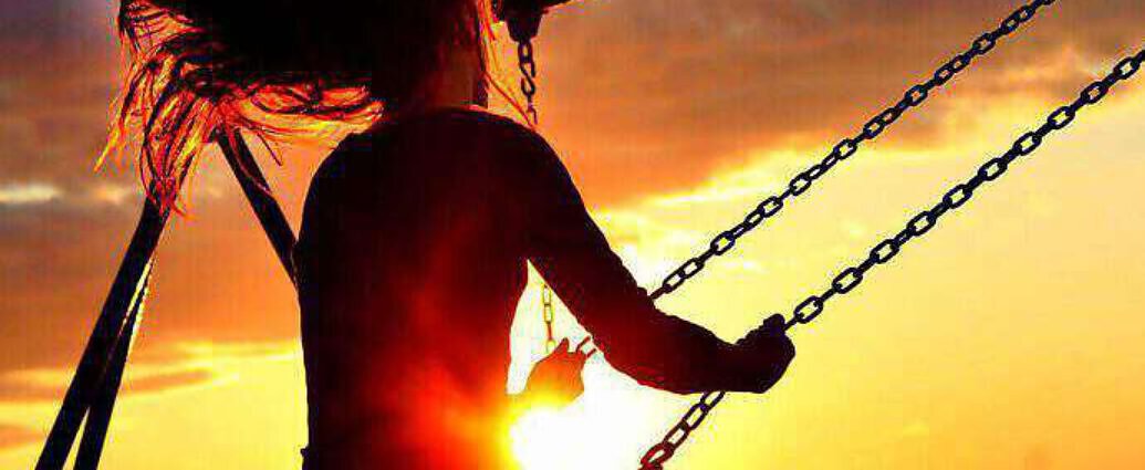 Eine junge Frau schaukelt dem Sonnenuntergang entgegen.