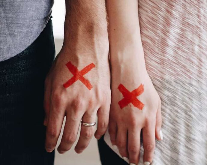 Ein Bild von den Händen einer Frau und eines Mannes, auf deren Hand jeweils ein rotes Kreuz gemalt ist.