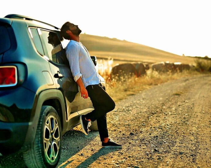 Ein Mann steht entspannt an seinem Auto.