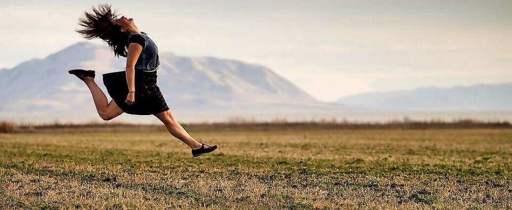 Eine junge Frau springt vor Freude in die Luft.