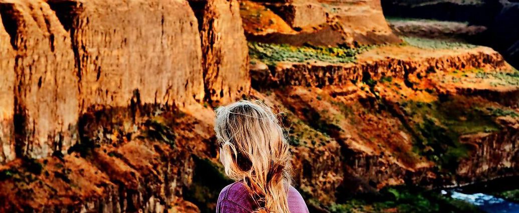Eine junge Frau steht am Rand einer Klippe.