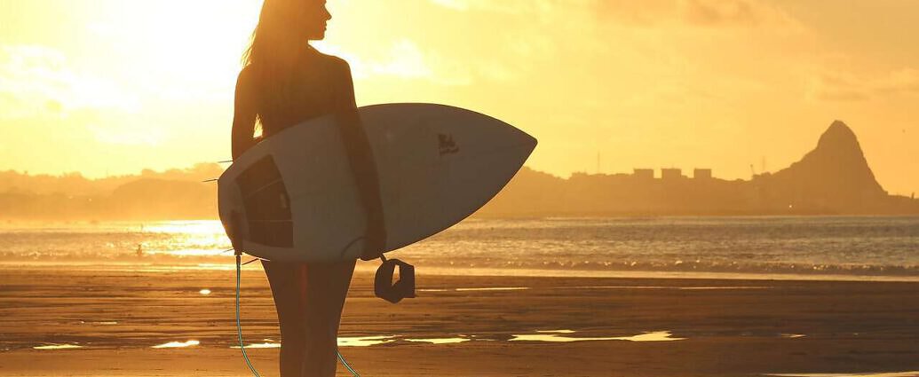Ein Bild einer Surferin am Strand von Carvoeiro, einem verschlafenen Küstenort an der Algarve in Portugal.