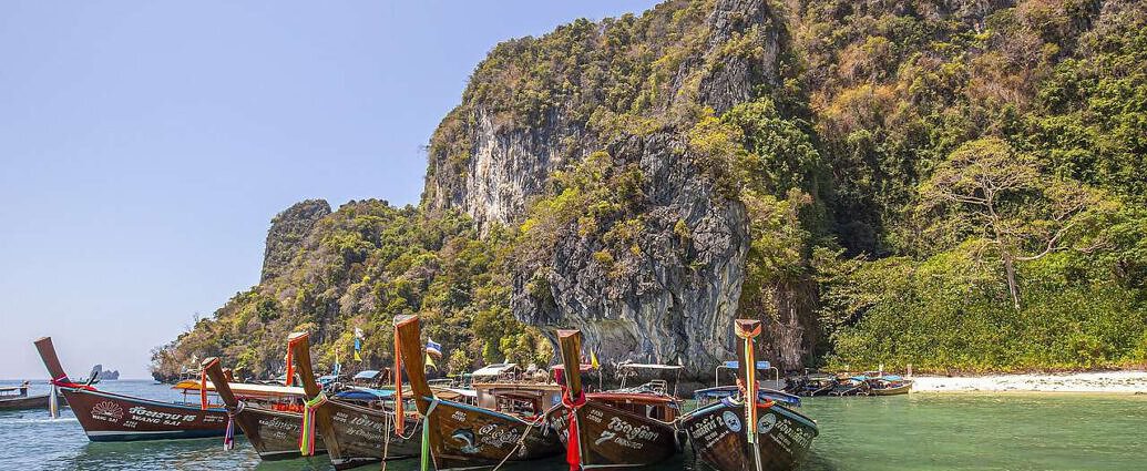 Direkt am Strand des Chao Phraya sind Longtail-Boote zu sehen.