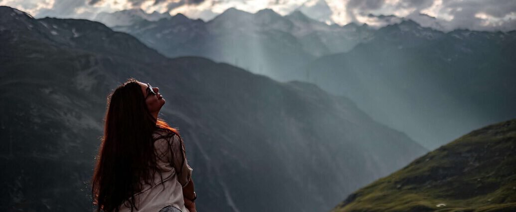 Eine junge Frau sitzt auf einem Felsen in Luzern. Vor ihr sind die Berge zu sehen.