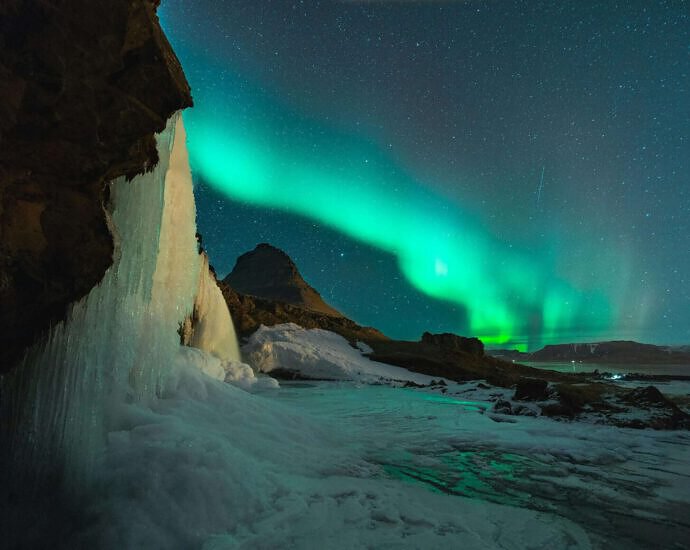 Ein Bild von Island mit seiner kalten, schneebedeckten Landschaft und den wunderschönen Nordlichtern am Himmel.