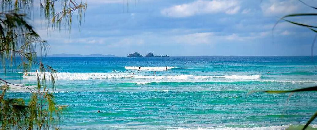 Ein Bild von einem schönen Strand mit Palmen und türkisfarbenem Ozean.