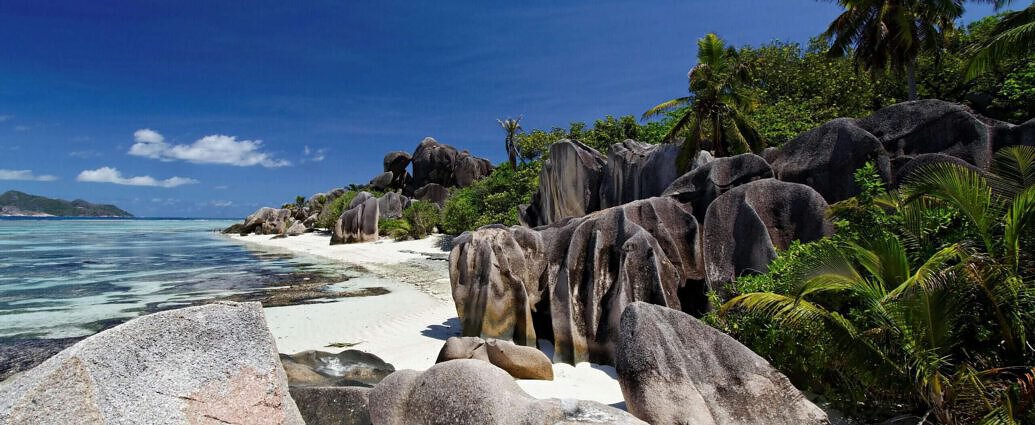 Ein Bild von Anse Lazio auf Praslin, Seychellen, mit seinen Granitfelsen, Palmen, Sand und dem Ozean.