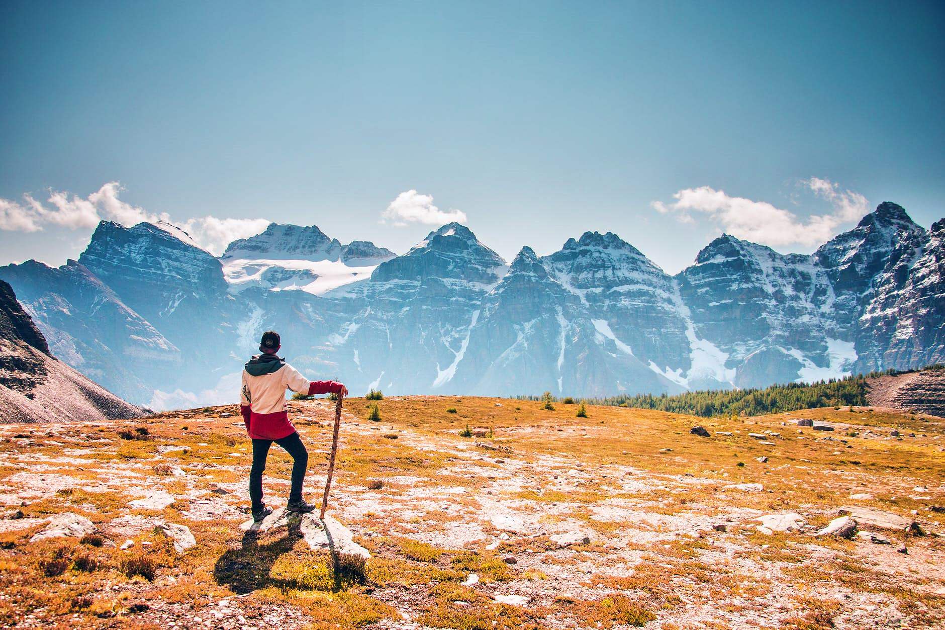 Ein Mann steht auf einem Bergweg und blickt auf die Großen Berge.