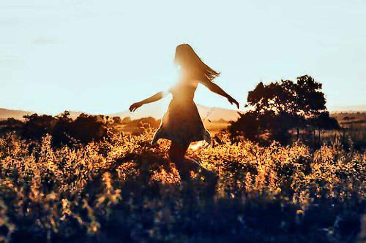 Eine Frau Tanzt im einen Blumenfeld