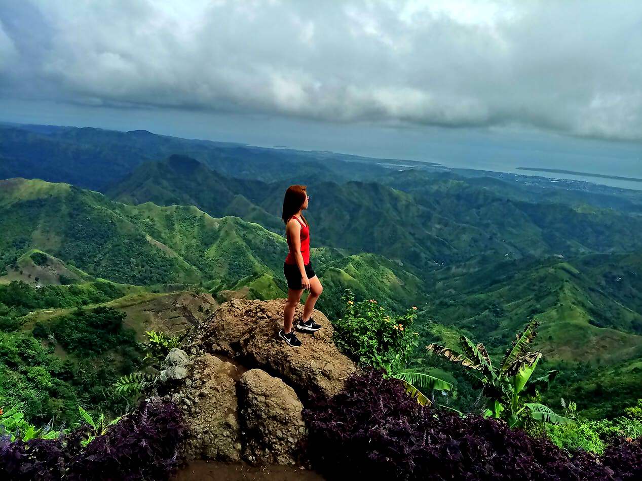 Frau schaut am Berganhang in die Ferne