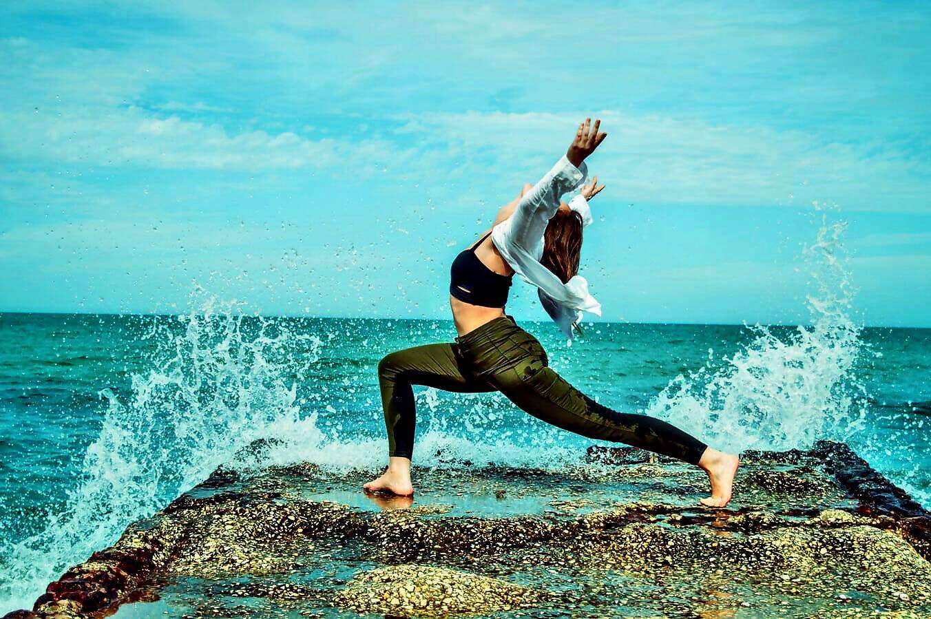 Eine junge Frau in grünen Jeans rekelt sich am Wasser.
