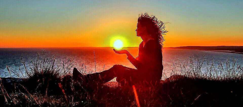 Eine Frau sitzt in der Abendsonne und blickt in die Ferne.