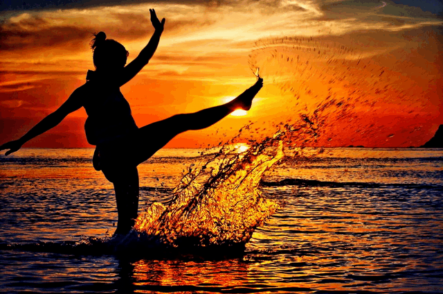 Frau spritz Wasser mit dem Füßen im Meer