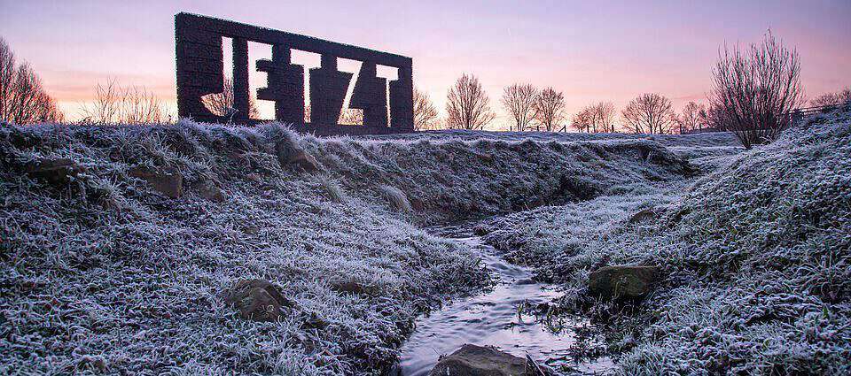 Eine Landschaft im Hintergrund ist eine Struktur mit dem Namen JETZT.