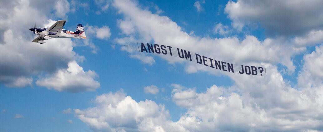 Ein Flugzeug mit einen Banner mit der Aufschrift: Was tun bei Angst um deinen Job?