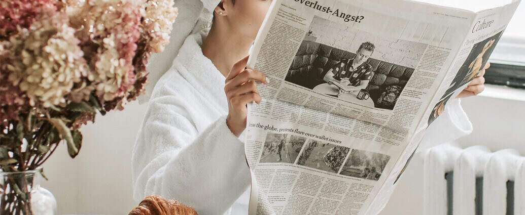 Frau im Morgenmantel liest Zeitung mit der Überschrift Jobverlust Angst.