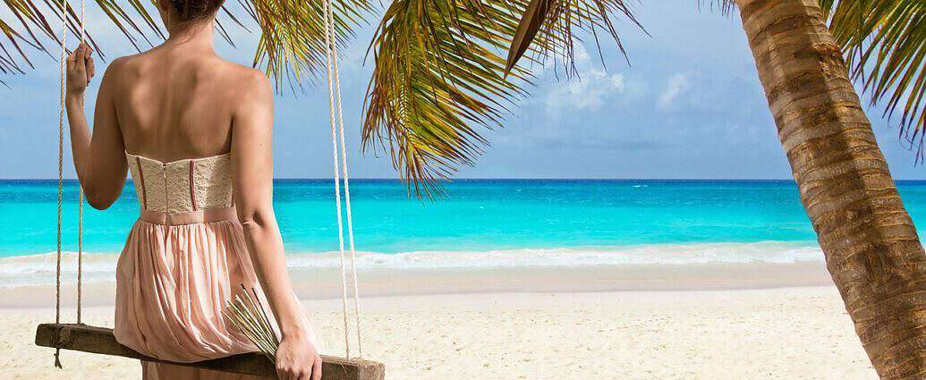 Eine Frau sitzt auf einer Schaukel am Strand.