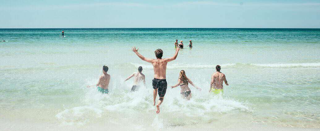 Ein Traumstrand mit badenden und fröhlichen Menschen.