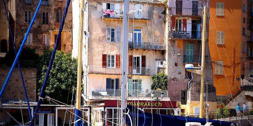 Ein Hafen in einem Küstendorf mit bunten Häusern und Booten davor.