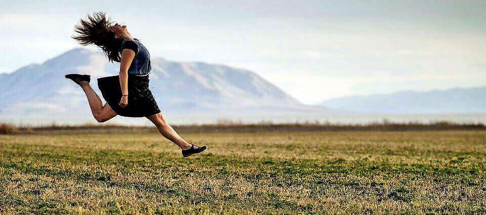 Eine junge Frau springt beim Laufen in die Luft.