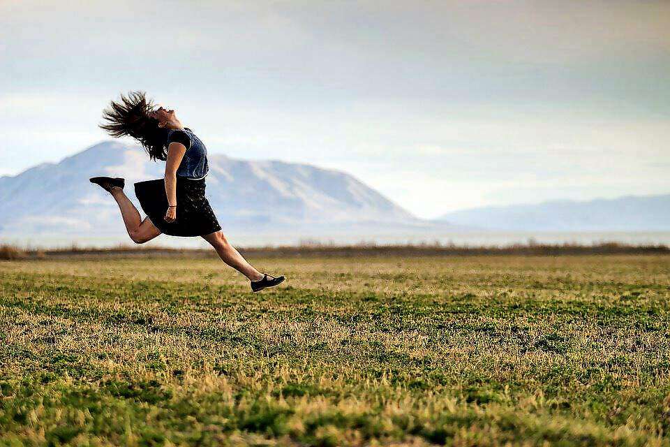 Eine junge Frau springt beim Laufen in die Luft.