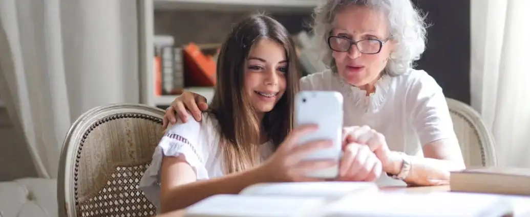 Eine alte Frau und ihre Engelin schauen in ein Smartphone.