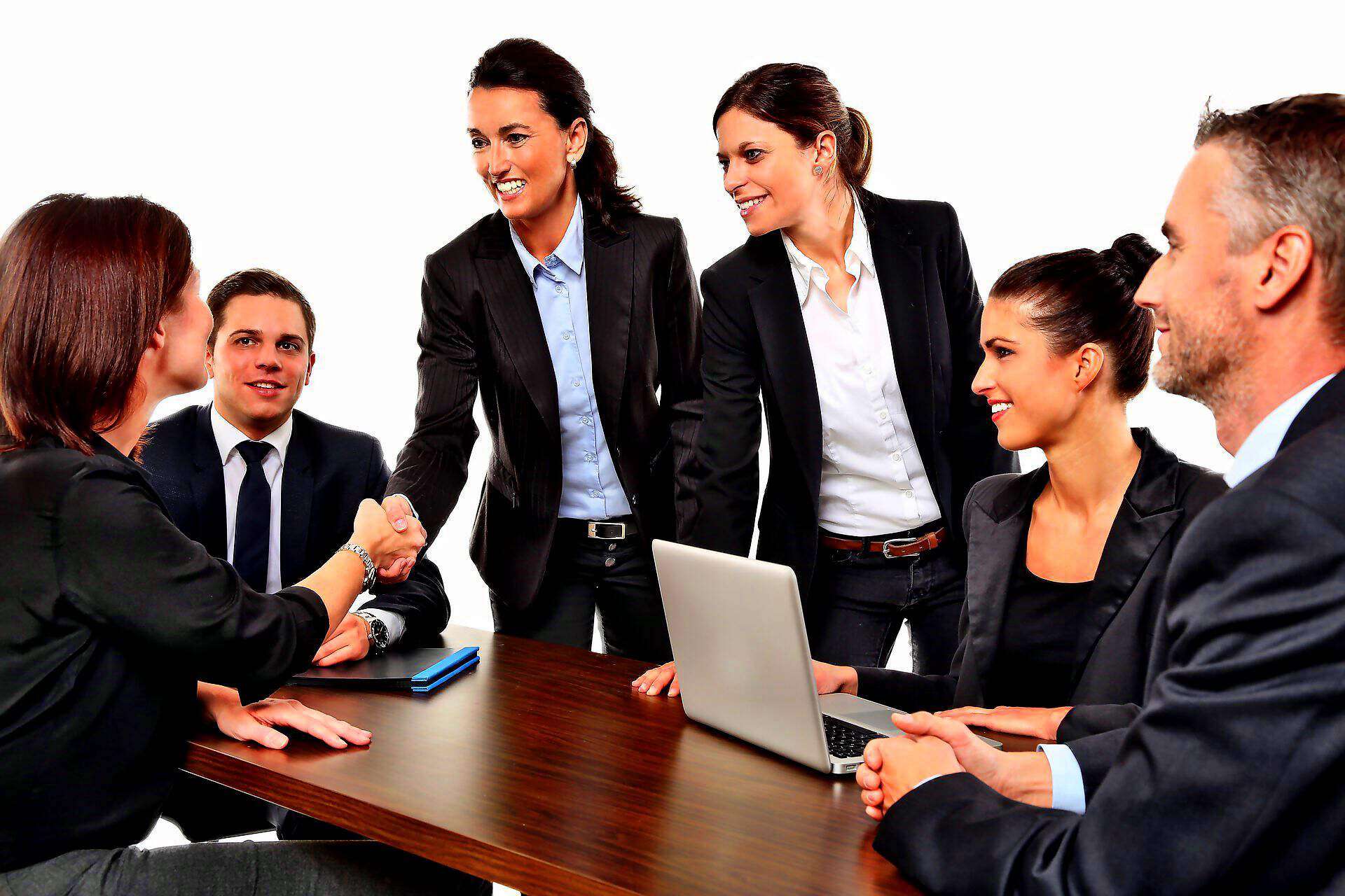 Zwei junge Business-Frauen stellen sich ihren Mentoren vor und lachen dabei.