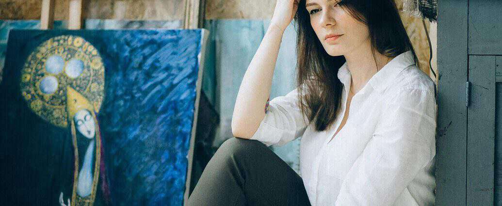 Nachdenklich blickt eine Künstlerin auf den Boden.