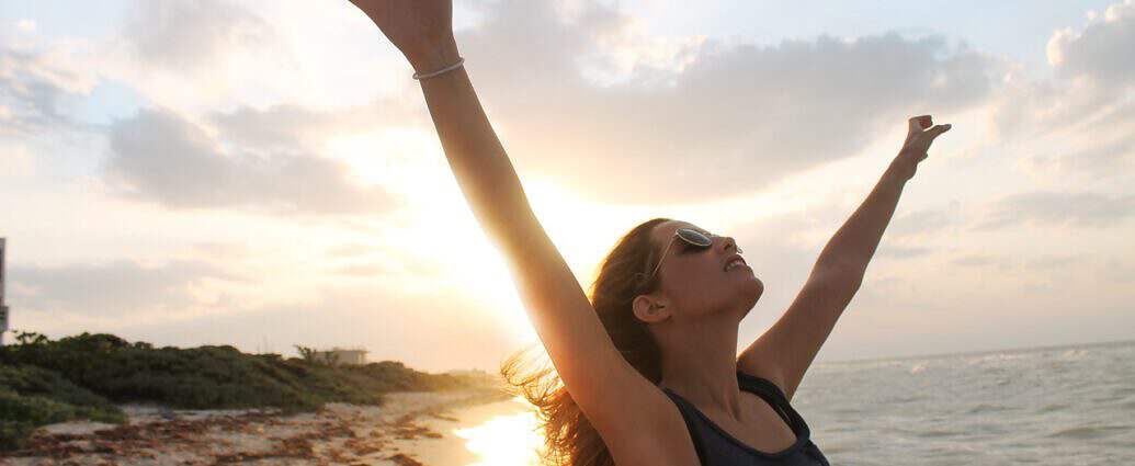 Eine junge Frau, die vor Freude ihre Arme in die Luft hält.