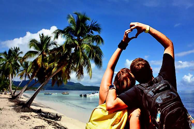 Ein Paar zeigt mit seinen Händen ein Herz auf einer schönen Insel.