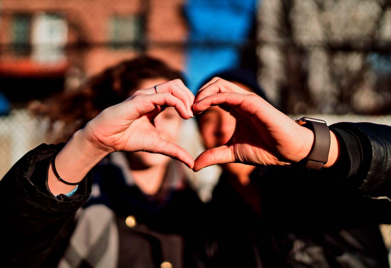 Eine junge Frau zeigt mit ihren Händen symbolisch ein Herz.
