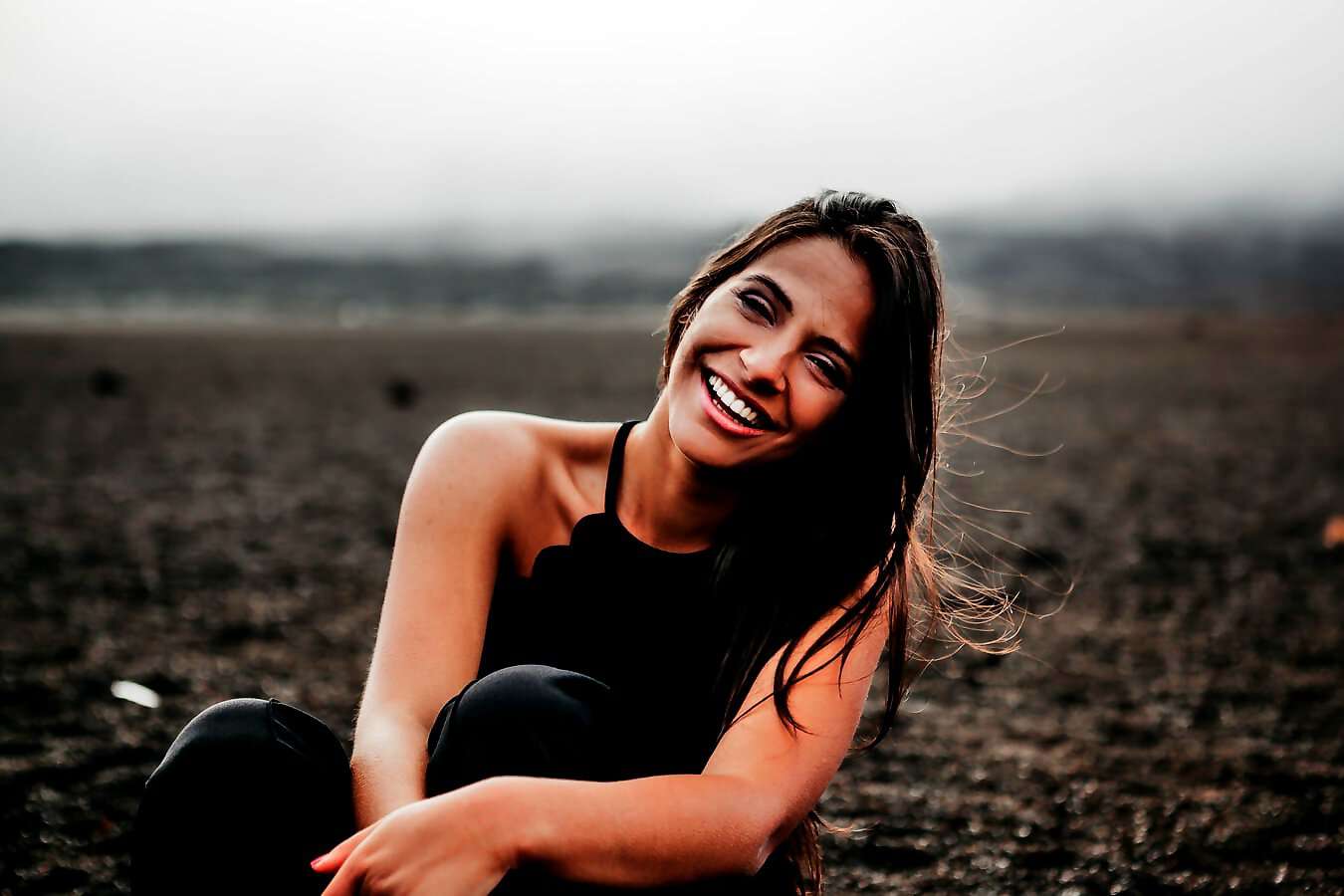 Eine junge Frau mit langen braunen Haaren lacht fröhlich.