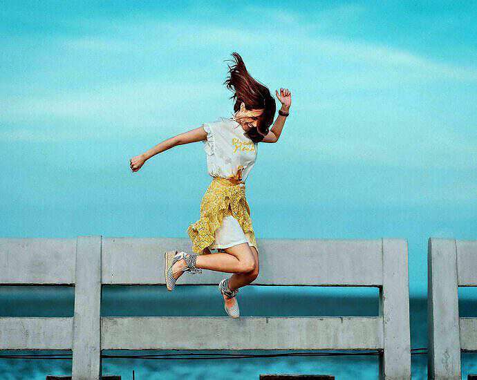 Eine junge Frau springt vor Freude in die Luft.