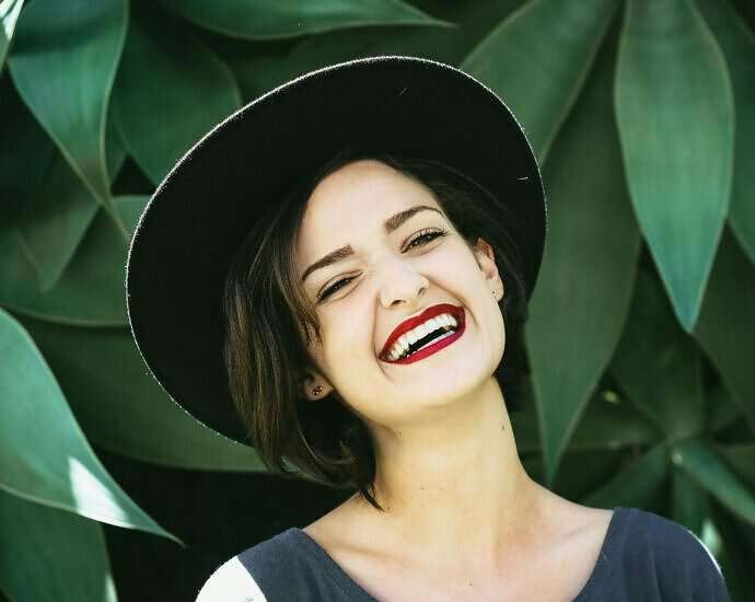 Eine junge Frau mit Hut, die von ganzem Herzen lacht.