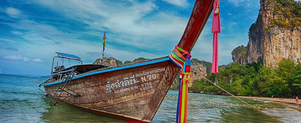 Ein Bild von Railay Beach in Krabi, Thailand, mit Palmen, Strand und Meer.