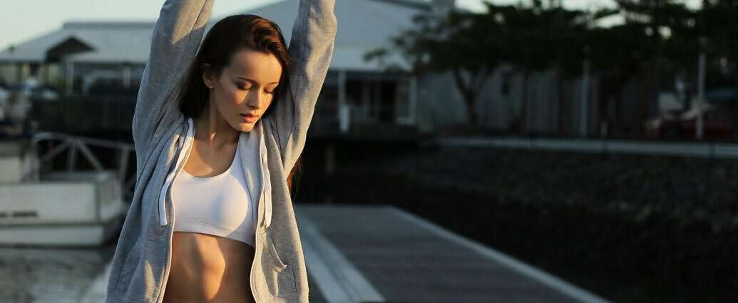 Eine junge Frau, die sich vor dem Laufen etwas dehnt.