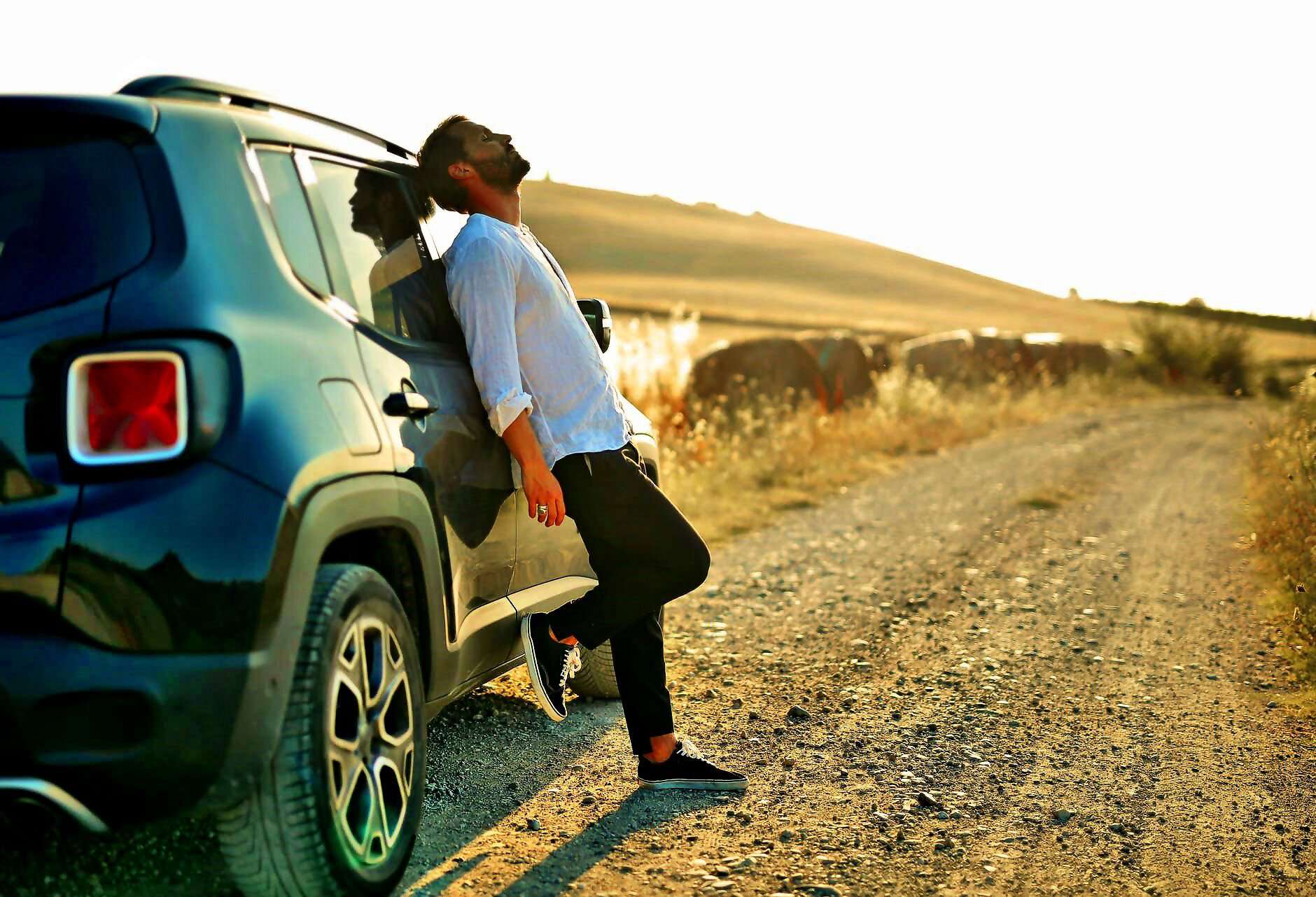 Ein Mann steht entspannt an seinem Auto.