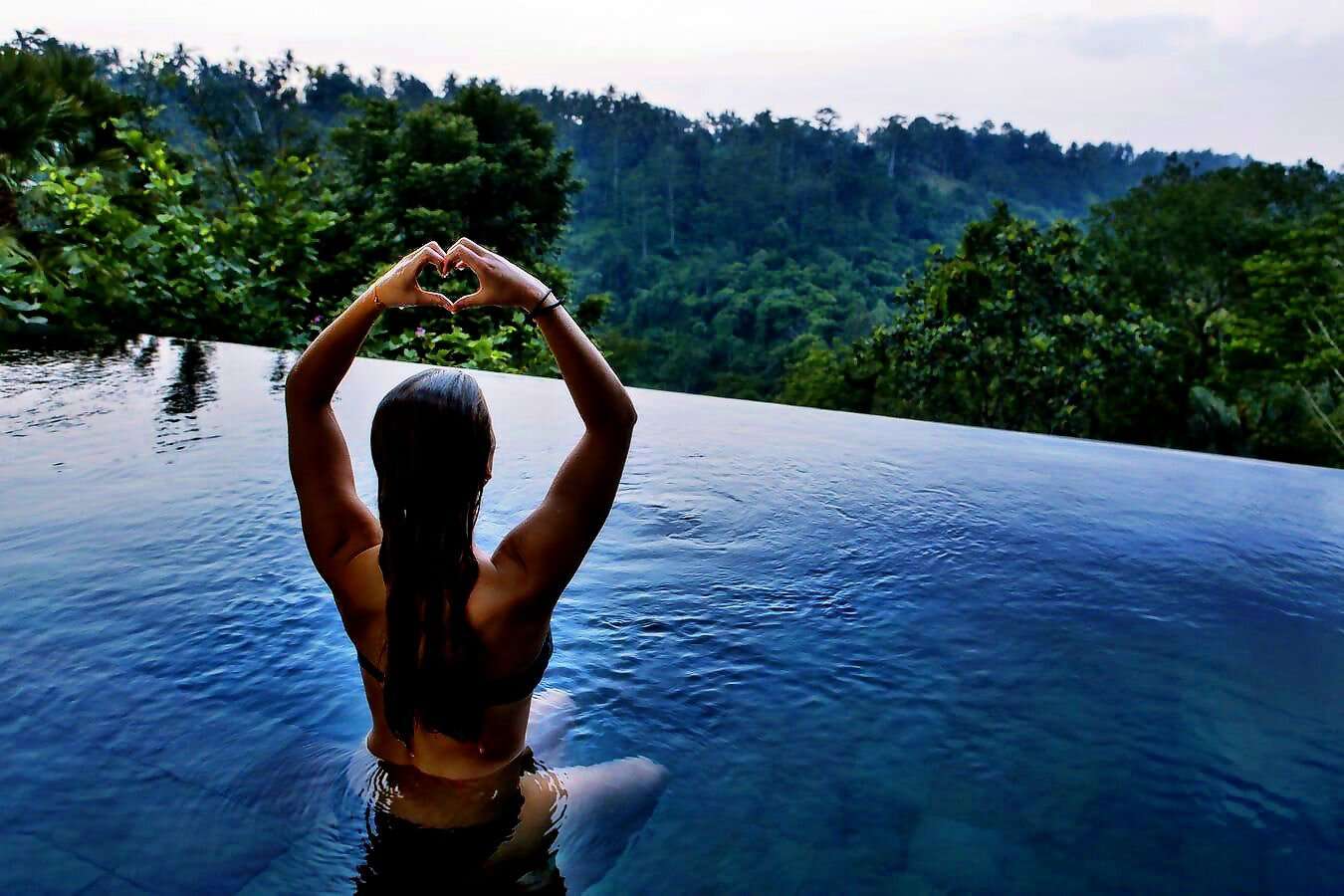Eine Frau in einen Pool mit Aussicht auf die Landschaft.