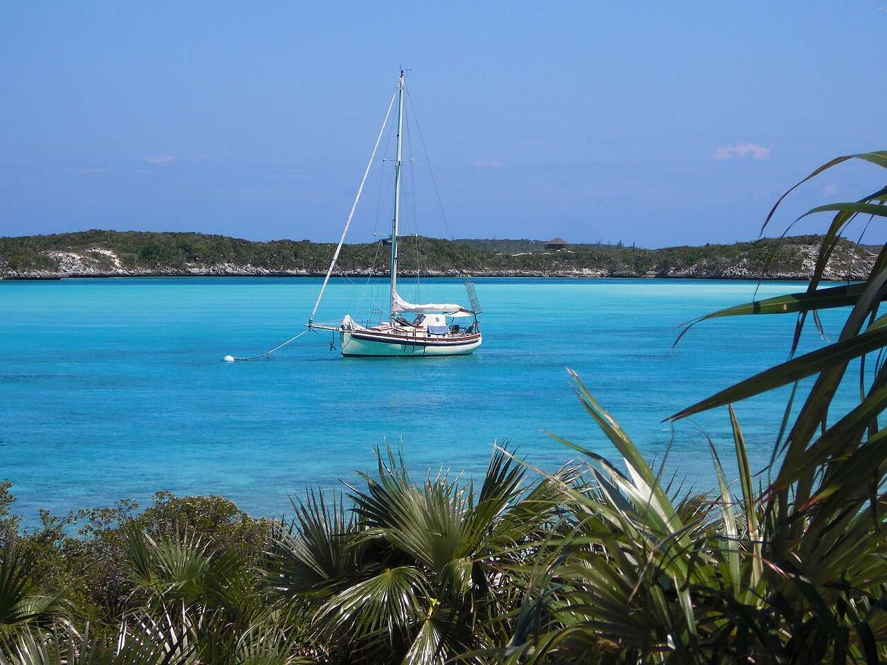 Ein Bild von den Exuma Cays auf den Bahamas: ein Blick auf das Meer mit einem kleinen Segelboot.